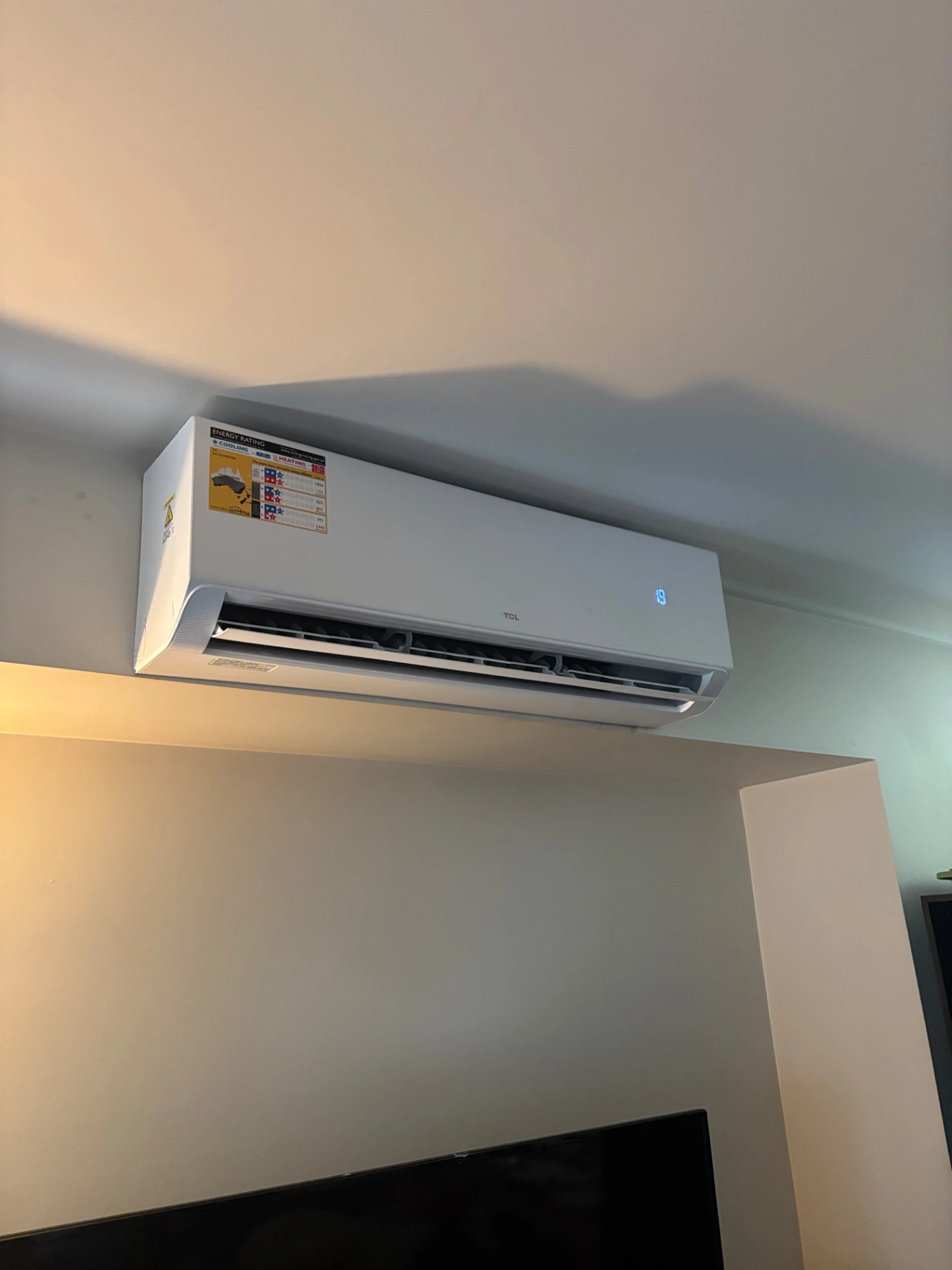 Wall-mounted split system air conditioner installed above a living room television