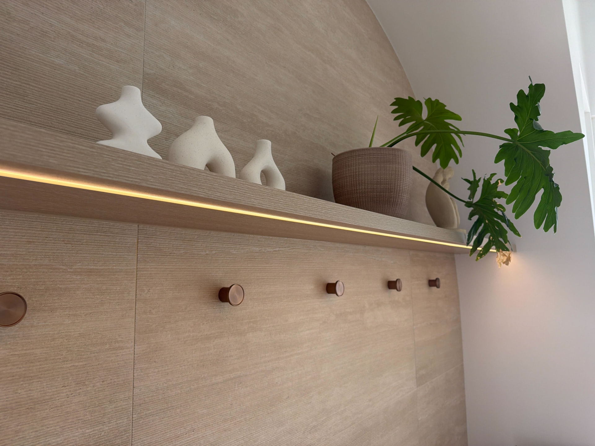 Concealed LED strip lighting under a floating timber shelf on a tiled wall